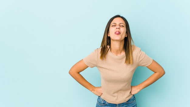 Jonge vrouw geïsoleerd op blauwe ruimte grappige en vriendelijke tong uitsteekt.