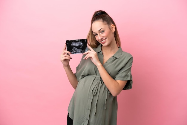 Jonge vrouw geïsoleerd op roze achtergrond zwanger en met een echografie