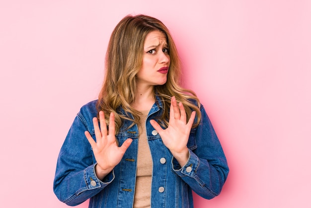 Jonge vrouw geïsoleerd op roze iets te verwerpen