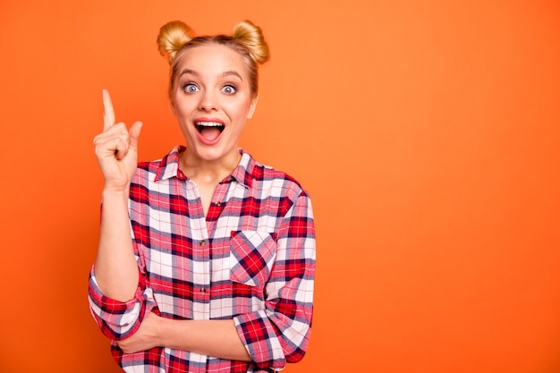 jonge vrouw gekleed in een geruite geruit hemd geïsoleerd op oranje