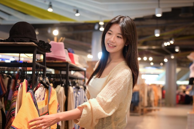 Jonge vrouw gekleed in een lichte casual outfit die geniet van een winkelen in een trendy kledingwinkel