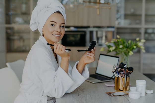 jonge vrouw geldt make-up cosmetica met borstel voor spiegel