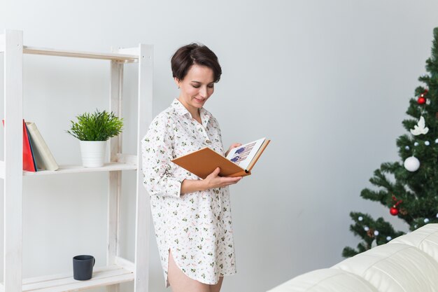 Jonge vrouw gelezen boek in woonkamer met kerstboom