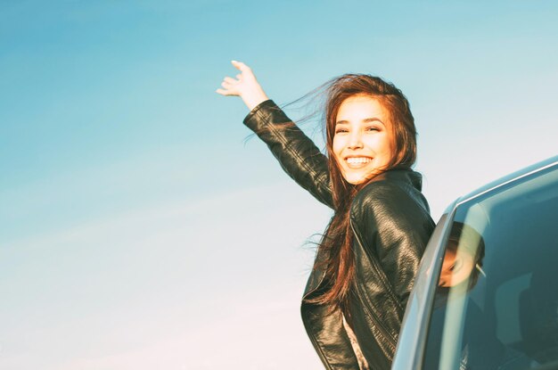 Jonge vrouw geniet van een roadtrip tegen de lucht.