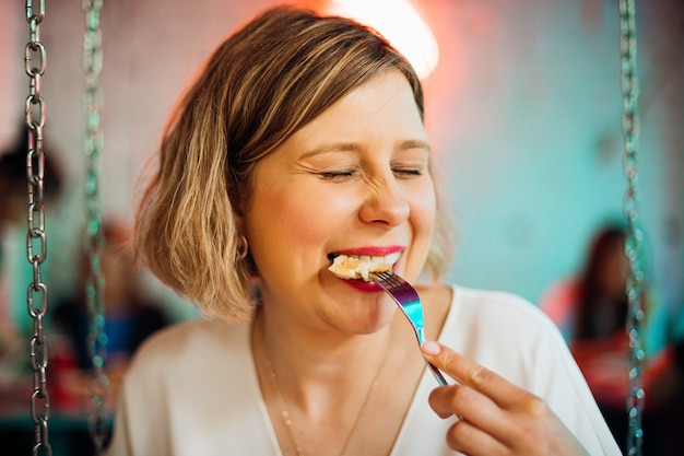 Jonge vrouw geniet van maaltijd zitten in café. Concept van goede voeding. Recreatie en amusement.