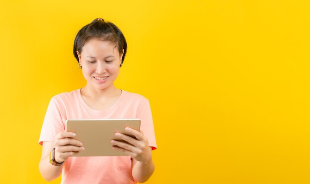 Jonge vrouw geniet van online winkelen gelukkig thuis tegen gele achtergrond