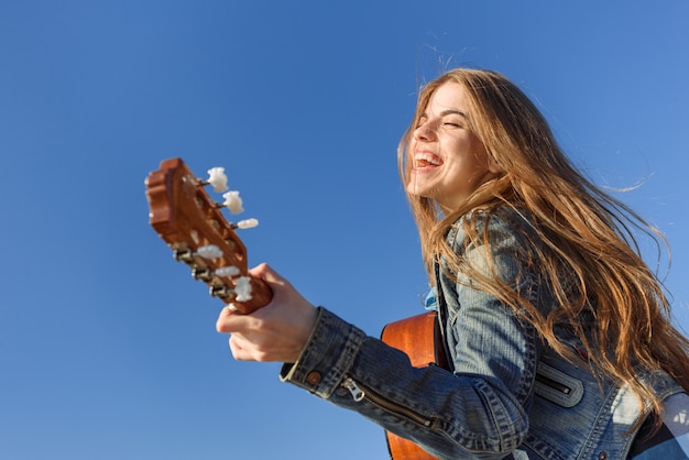 Jonge vrouw genieten van gitaar spelen.