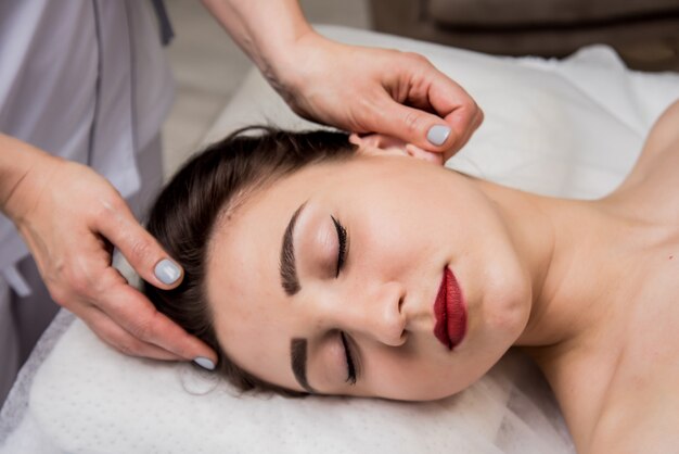 jonge vrouw genieten van hoofdmassage in spa salon. Cosmetologie