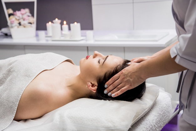 jonge vrouw genieten van hoofdmassage in spa salon. Cosmetologie