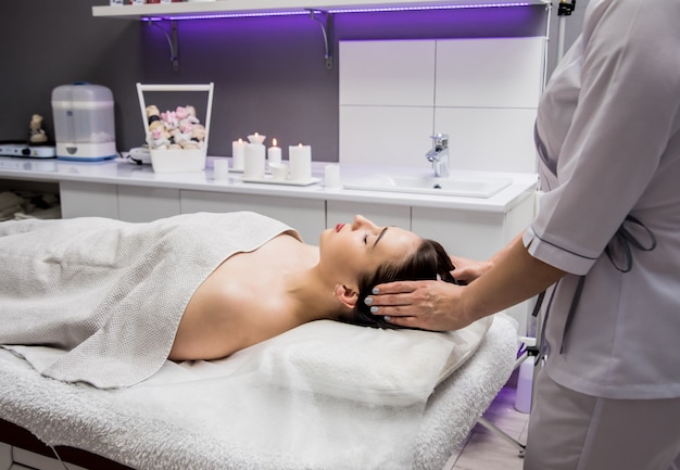 jonge vrouw genieten van hoofdmassage in spa salon. Cosmetologie