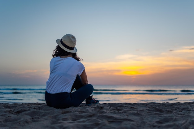 Jonge vrouw genieten van prachtige zonsondergang boven de zee