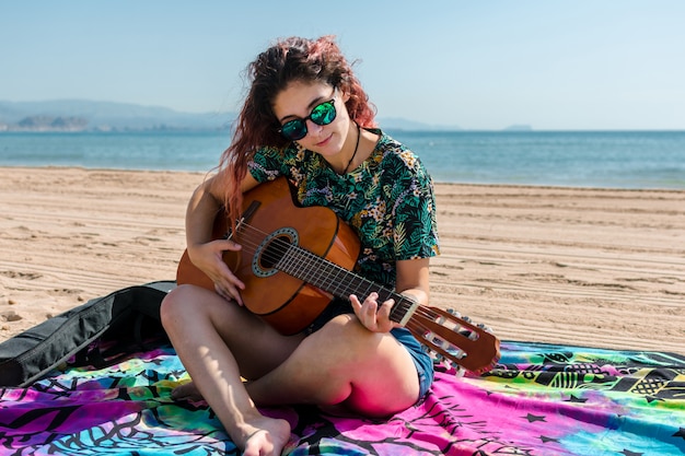 Jonge vrouw gitaarspelen op het strand