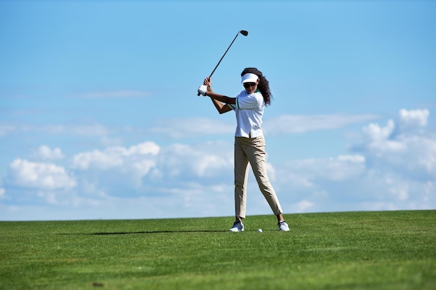 Jonge vrouw golfen op groen veld tegen lucht en swingende golfclub