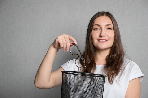 Jonge vrouw gooit bril in de vuilnisbak