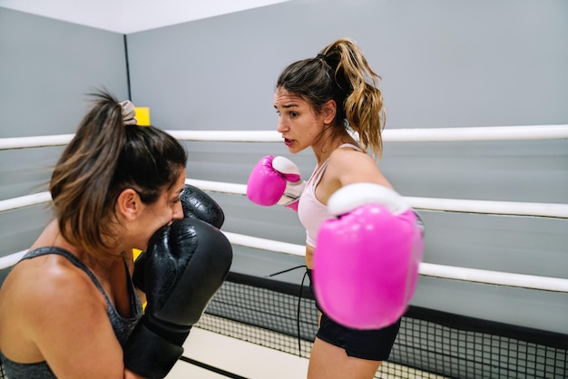 Jonge vrouw gooit een zijstoot naar haar partner in een boksoefening in de ring