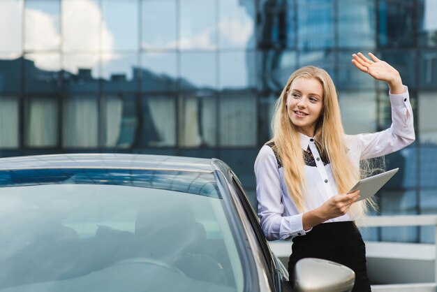 Jonge vrouw groet iemand met hand omhoog