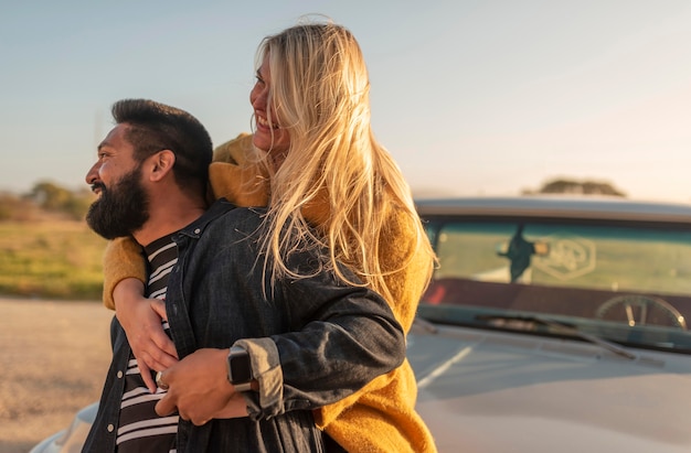 Jonge vrouw haar vriendje van achteren knuffelen tijdens het verblijf op de auto