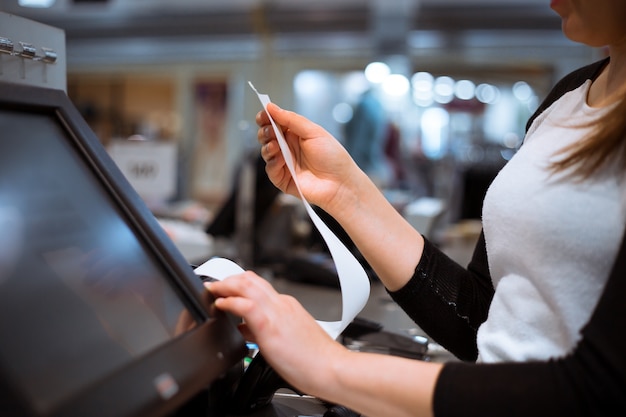 Jonge vrouw handen scannen / korting / verkoop invoeren op een bon, touchscreen kassa, markt / winkel