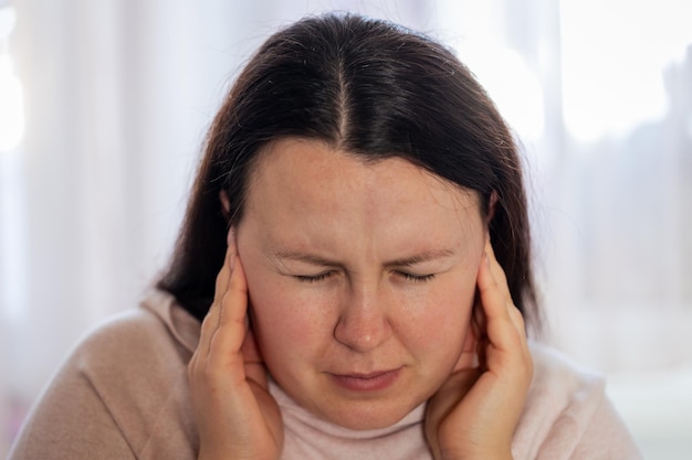 Jonge vrouw heeft hoofdpijn migraine stress of tinnitusgeluid fluitend in haar oren