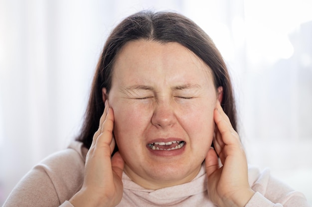 Jonge vrouw heeft hoofdpijn, migraine, stress of tinnitusgeluid in haar oren