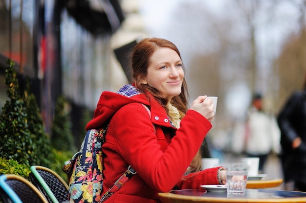 Jonge vrouw het drinken koffie in een Parijse straatkoffie bij de de lentedag