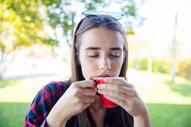 Jonge vrouw het drinken koffie in het park