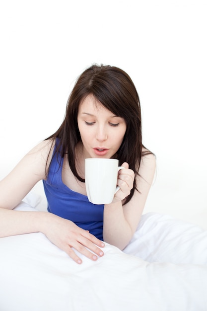 Jonge vrouw het drinken koffiezitting op bed