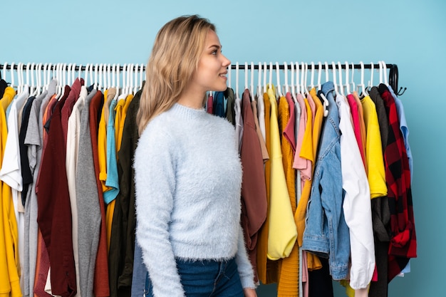 Jonge vrouw het kopen kleren over geïsoleerde muur