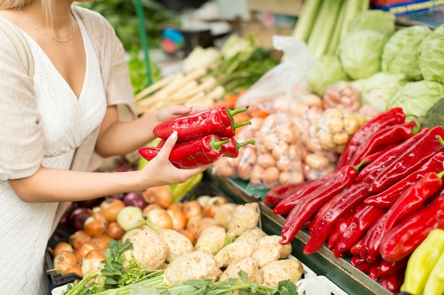 Jonge vrouw het kopen van groenten op de markt