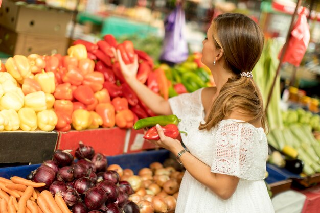 Jonge vrouw het kopen van groenten op de markt