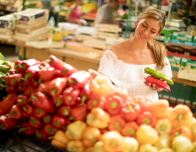 Jonge vrouw het kopen van groenten op de markt