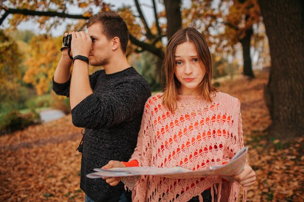 Jonge vrouw houd kaart en kijk naar camer.a Ze is gefrustreerd. Kerel kijkt in verrekijker. Ze verkennen.