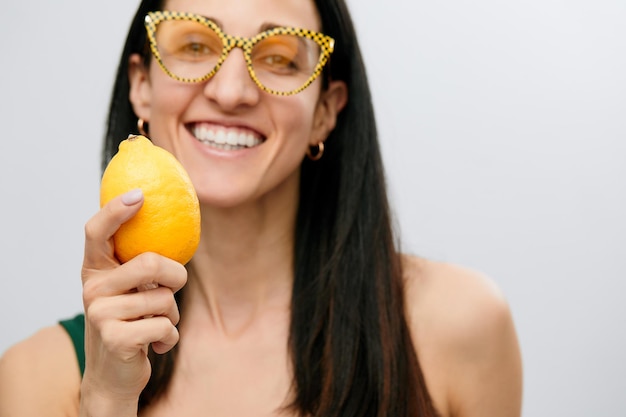 Jonge vrouw houdt citroen rauwe verse gele citrusvruchten vrouwelijke gelukkige glimlach geïsoleerd op een witte achtergrond natuurlijke biologische voeding concept