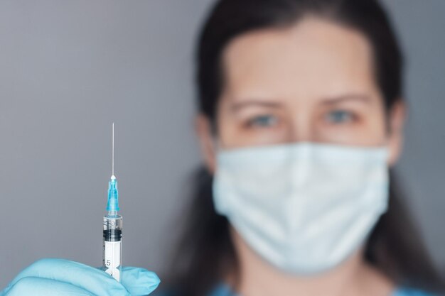 Jonge vrouw houdt flesje coronavirusvaccin in de hand Focus op hand met flesje