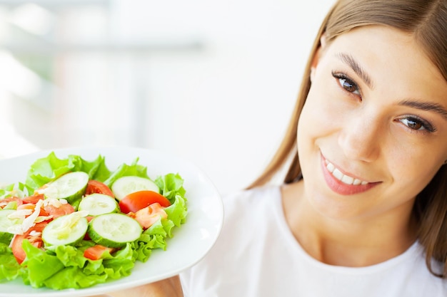 Jonge vrouw houdt gezonde salade met groene verse ingrediënten.