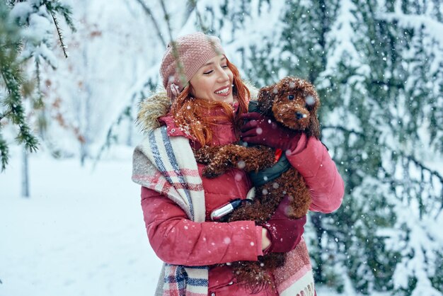 Jonge vrouw houdt haar mooie puppy vast en geniet samen van de winterdag buiten