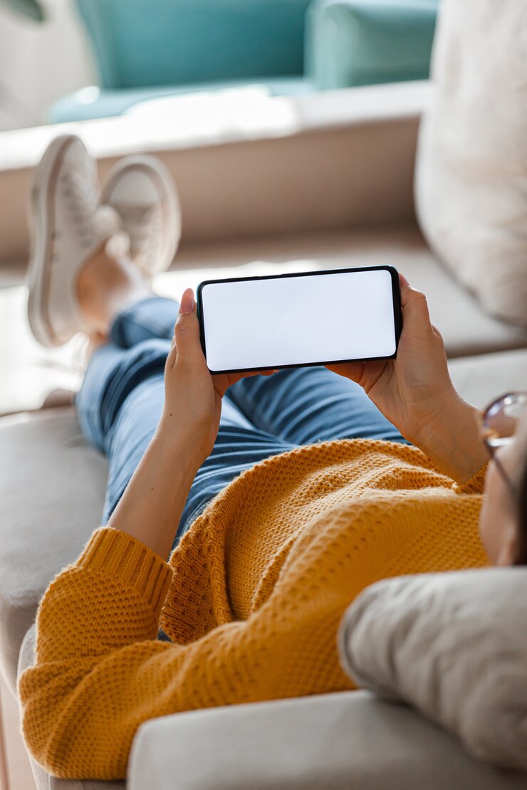Foto jonge vrouw houdt mobiele telefoon in handen, liggend op de bank