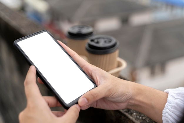Jonge vrouw houdt smartphone met wit scherm vast terwijl ze op een bank zit Buitenshuis vrouw die een telefoon gebruikt in de stad
