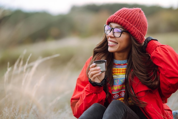 Jonge vrouw houdt thermos drinkt thee in herfst bos Rest ontspanning reizen levensstijl concept