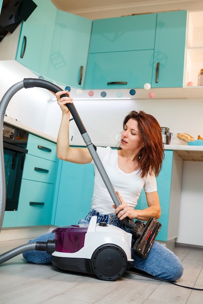 Jonge vrouw huisvrouw speelt met een stofzuiger. Leuke appartement schoonmaak