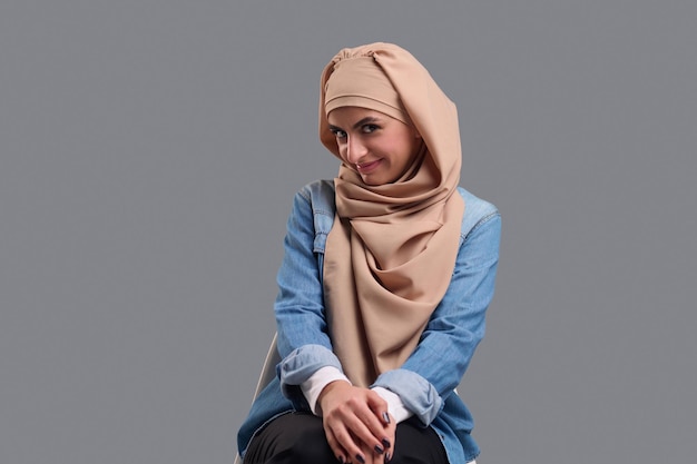 Foto jonge vrouw in beige hijab die er schattig en glimlachend uitziet