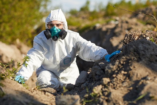 Jonge vrouw in beschermend pak en masker die als ecoloog werken. ze onderzoekt de natuur