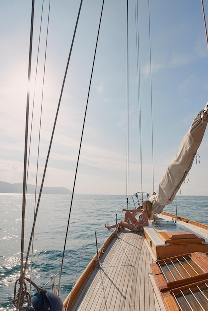 Jonge vrouw in bikini ontspannen zonnebaden op een boot Vrouw op een boot zonnebaden genieten van de zon Jonge tevreden vrouw zonnebaden op een boot