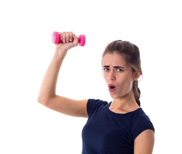 Jonge vrouw in blauw T-shirt met roze halter in haar hand op een witte achtergrond in studio