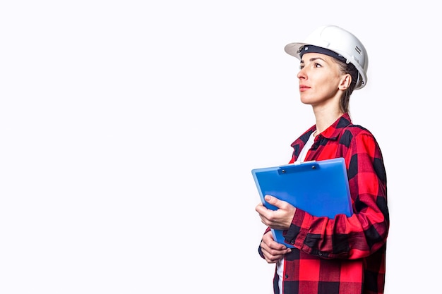 Jonge vrouw in bouwkleren met klembord op lichte achtergrond.