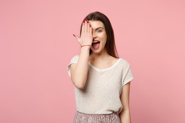 Jonge vrouw in casual lichte kleding poseren geïsoleerd op roze muur achtergrond studio portret. Mensen oprechte emoties levensstijl concept. Bespotten kopie ruimte. Mond open houden, gezicht bedekken met hand.