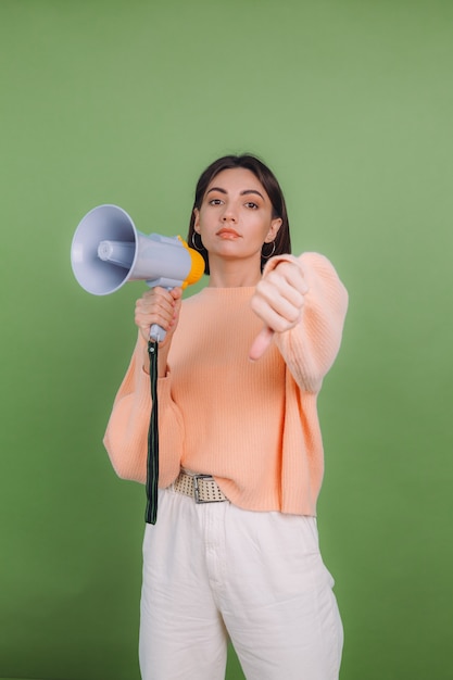 Jonge vrouw in casual perzik trui geïsoleerd op groene olijf kleur muur