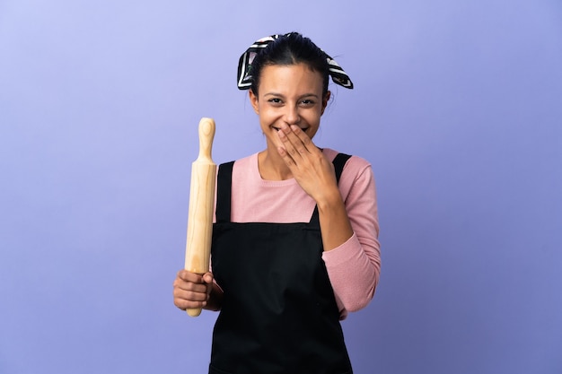 Jonge vrouw in chef-kok eenvormige gelukkig en glimlachend behandelend mond met hand