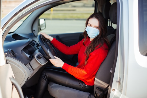 Jonge vrouw in coronavirus masker zitten in de auto