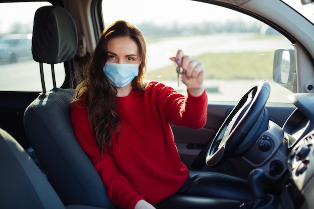 Jonge vrouw in coronavirus masker zitten in de auto